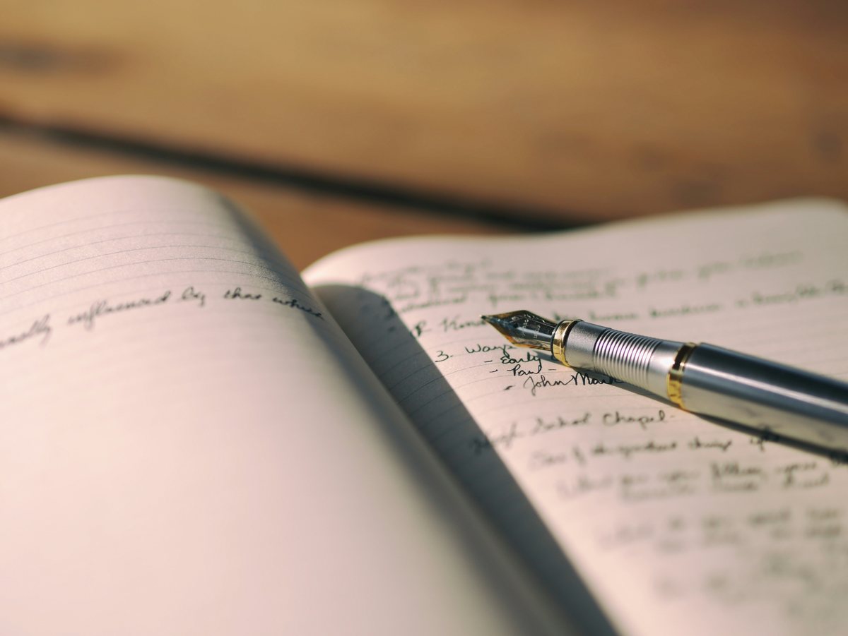 An open commonplace book with a pen resting in the gutter.